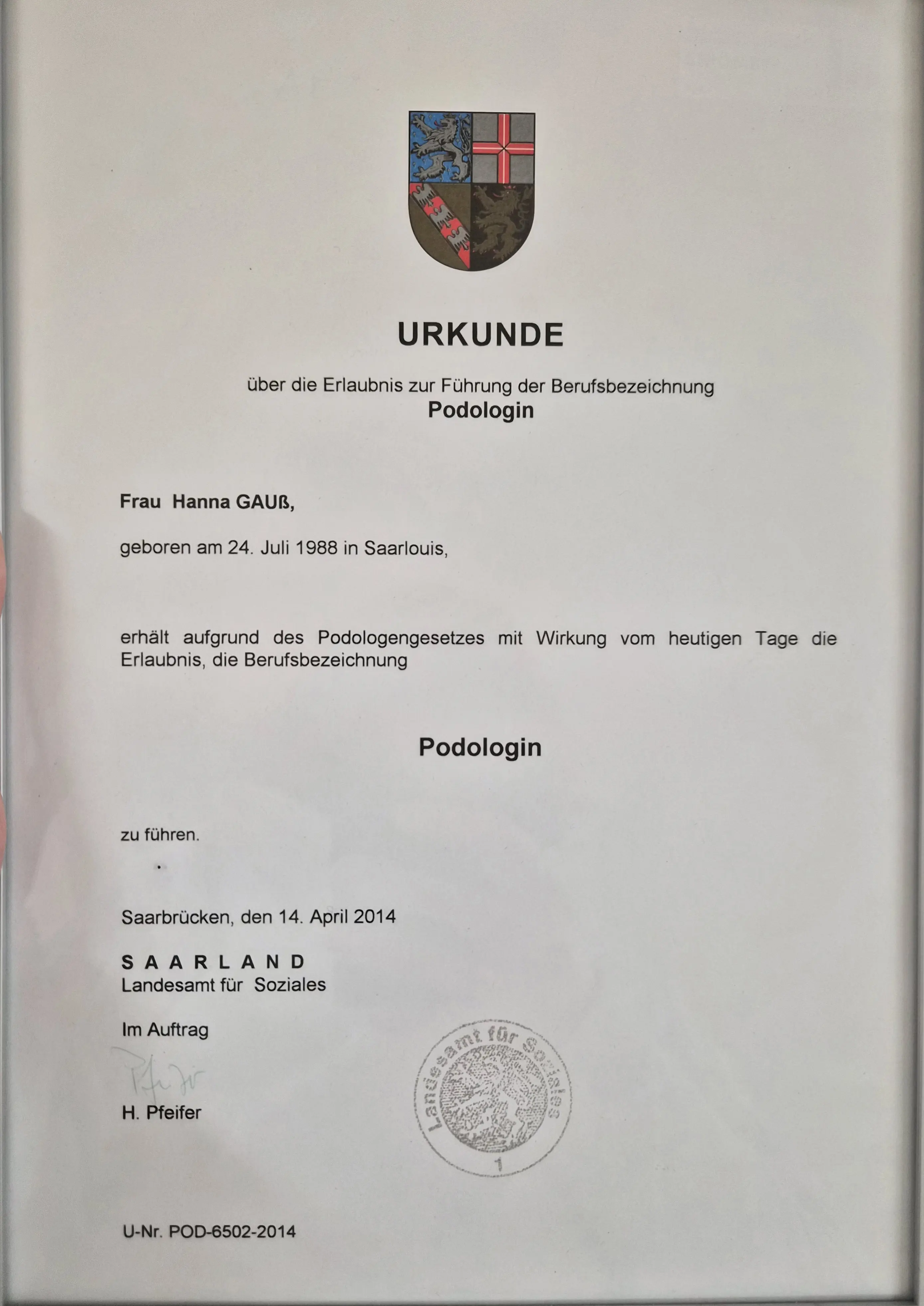 Das Bild zeigt eine offizielle Urkunde zur Führung der Berufsbezeichnung „Podologin“. Die Urkunde wurde vom Saarland – Landesamt für Soziales ausgestellt und bestätigt, dass Frau Hanna Gauß die Erlaubnis erhalten hat, die Berufsbezeichnung Podologin zu führen. Das Dokument trägt das Landeswappen, ein amtliches Siegel sowie die Ausstellung vom 14. April 2014 in Saarbrücken.