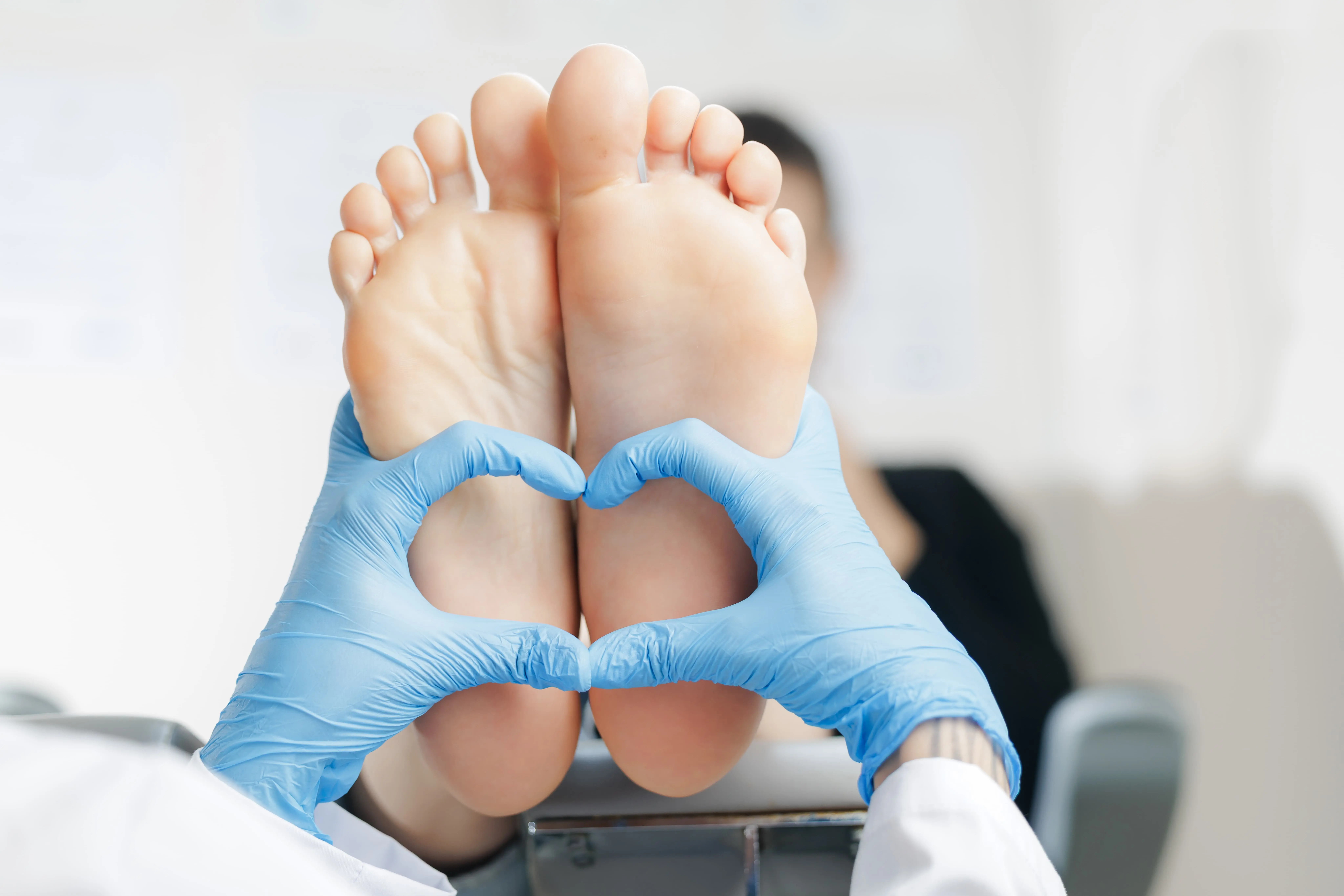 Das Bild zeigt die Fußsohlen eines Patienten während einer podologischen Behandlung. Die Füße werden von einer Fachkraft mit Handschuhen professionell gehalten und untersucht. Die Aufnahme vermittelt Pflege, Aufmerksamkeit und das Ziel, die Fußgesundheit nachhaltig zu erhalten.